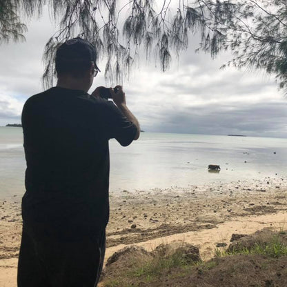 Man in hat with camera taking photo of pig in low tide